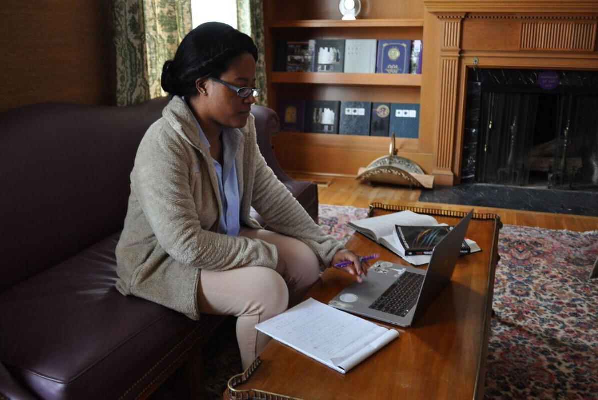 A female graduate student works on a laptop in a lounge area