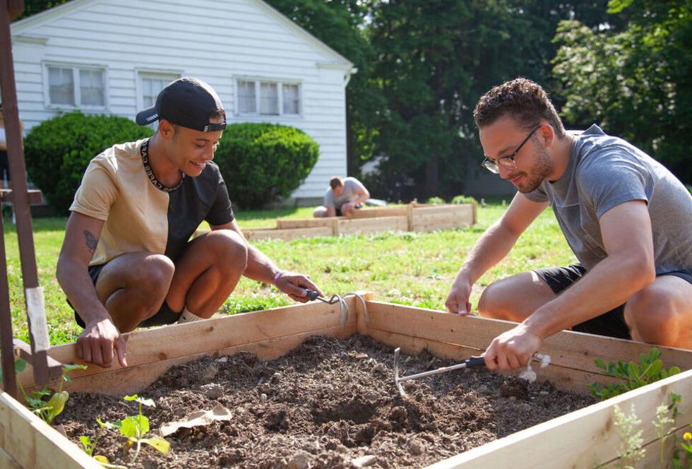 Two male students tend to the community garden on campus